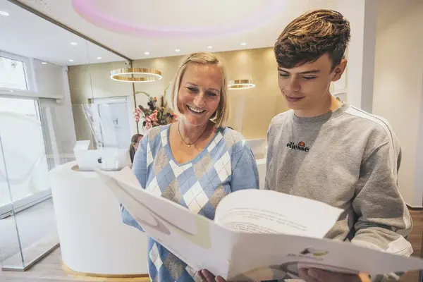 Zwei Personen lesen gemeinsam in einer modernen Zahnarztpraxis Informationsunterlagen.