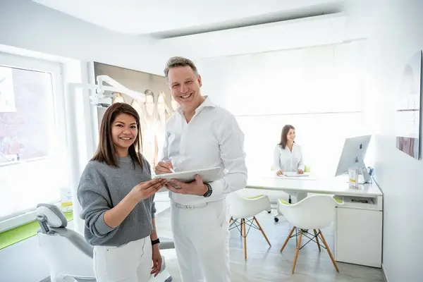 Zahnarzt berät Patientin freundlich in moderner Zahnarztpraxis mit heller Einrichtung.