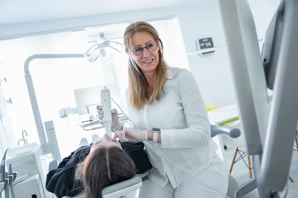 Zahnärztin untersucht Patientin mit modernem Scanner in heller Zahnarztpraxis.